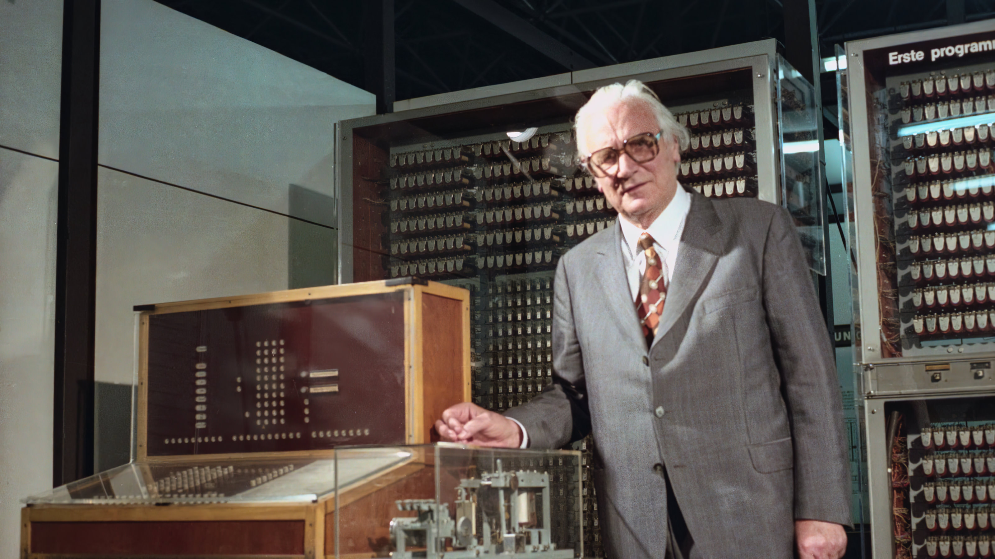 [A man standing next to a historical computing machine]